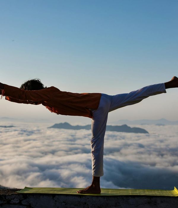 Silhouette of a person in a powerful warrior yoga pose at sunrise.